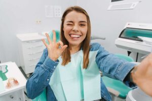 A person examining their teeth and gums in a bathroom mirror for signs of dental issues.