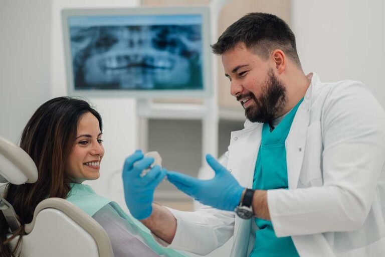 Person gently guiding dental floss between teeth in a well-lit bathroom.
