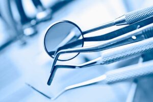 Person gently brushing teeth with a soft toothbrush beside a glass of cool water.